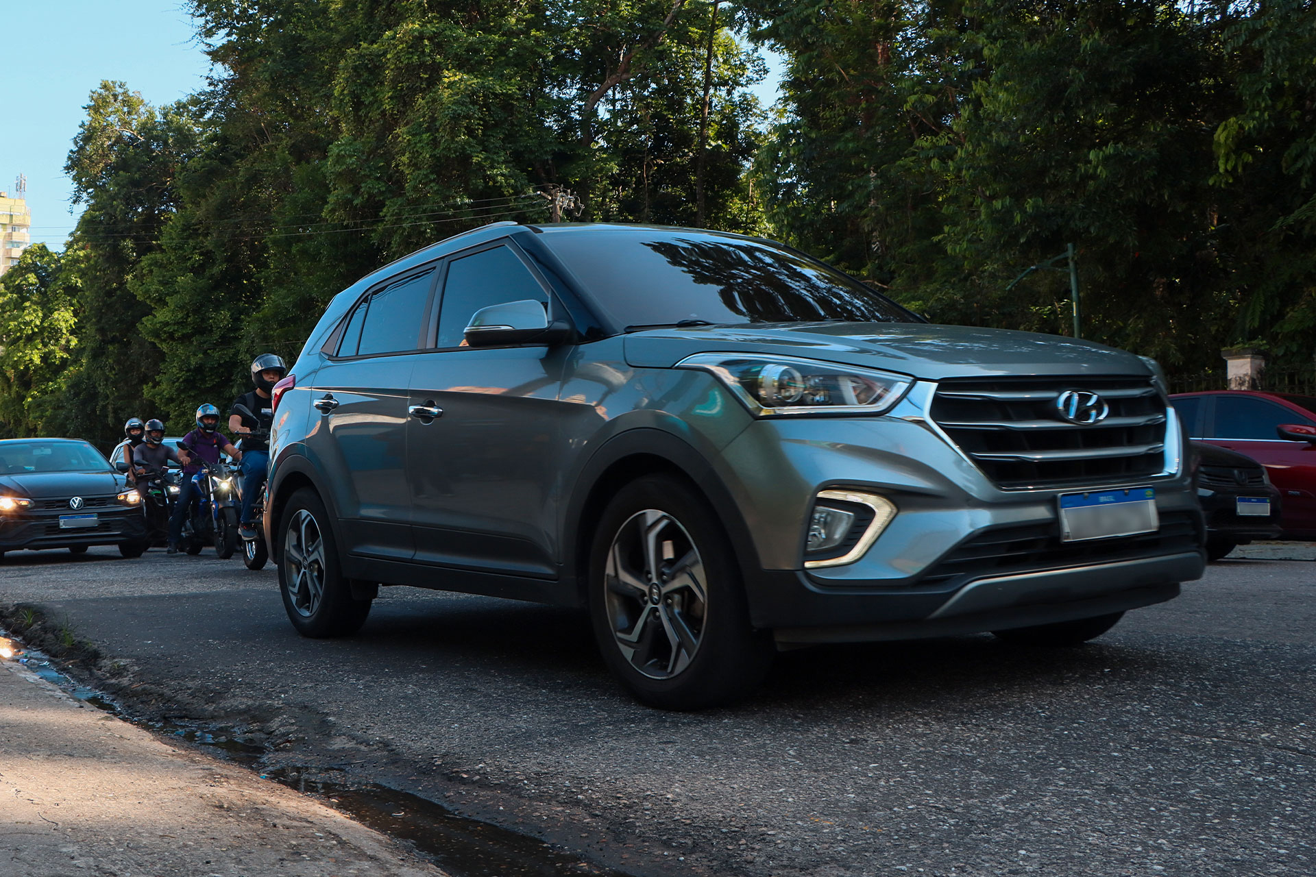 Um Hyundai Creta cinza trafega por via esburacada de Belém, seguido por motociclistas e outros carros
